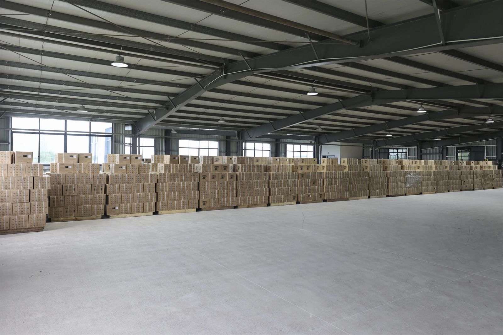 A spacious manufacturing warehouse and storage facility at Zhejiang Huiwenmei Stove Co., Ltd. (SSM), featuring extensive rows of packed product boxes ready for shipping, showcasing large-scale production and inventory capacity.