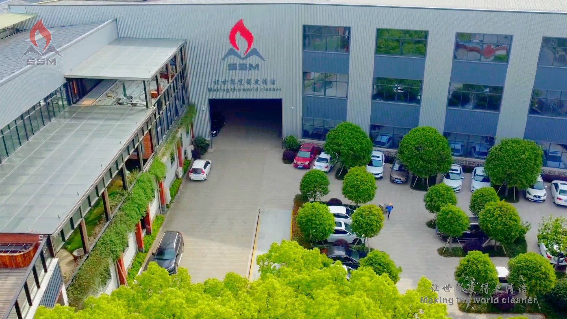 Aerial view of the Zhejiang Huiwenmei Stove Co., Ltd. (SSM) factory exterior, showing the modern corporate building, company branding logo, and surrounding parking area.