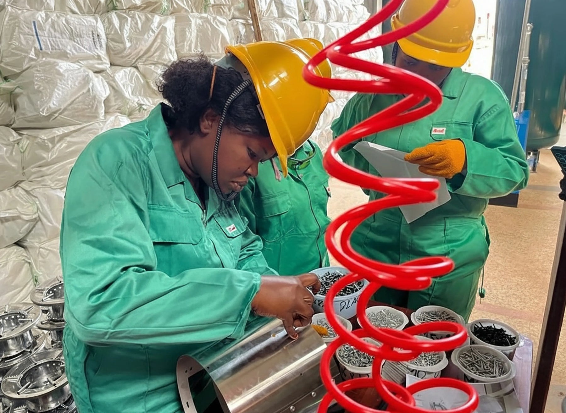 An all-female assembly line team meticulously assembling clean cookstoves using quality components in the Aru Region factory.